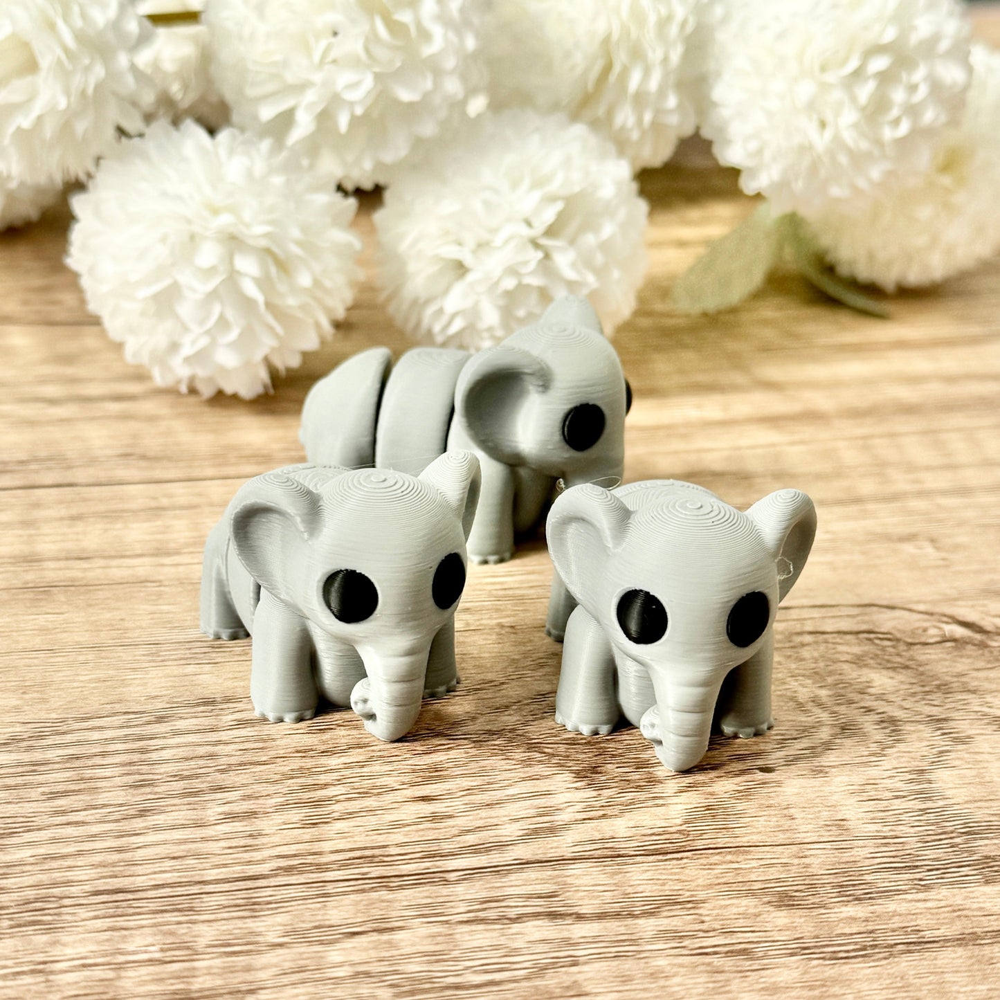 A grey elephant fidget toy with black eyes and a fully articulated body, measuring 5.5 cm in length.