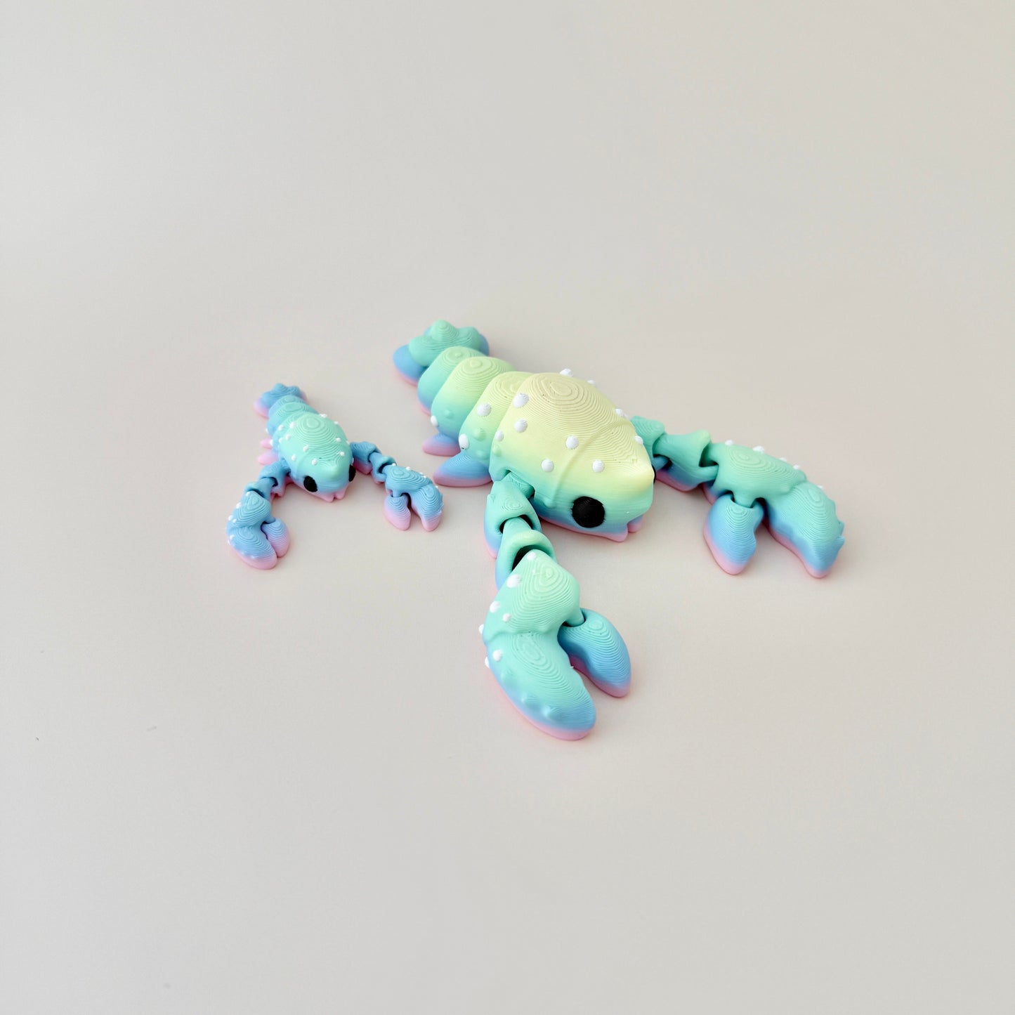 Lobster fidget toy available in red or rainbow, featuring flexible movement and sensory appeal.