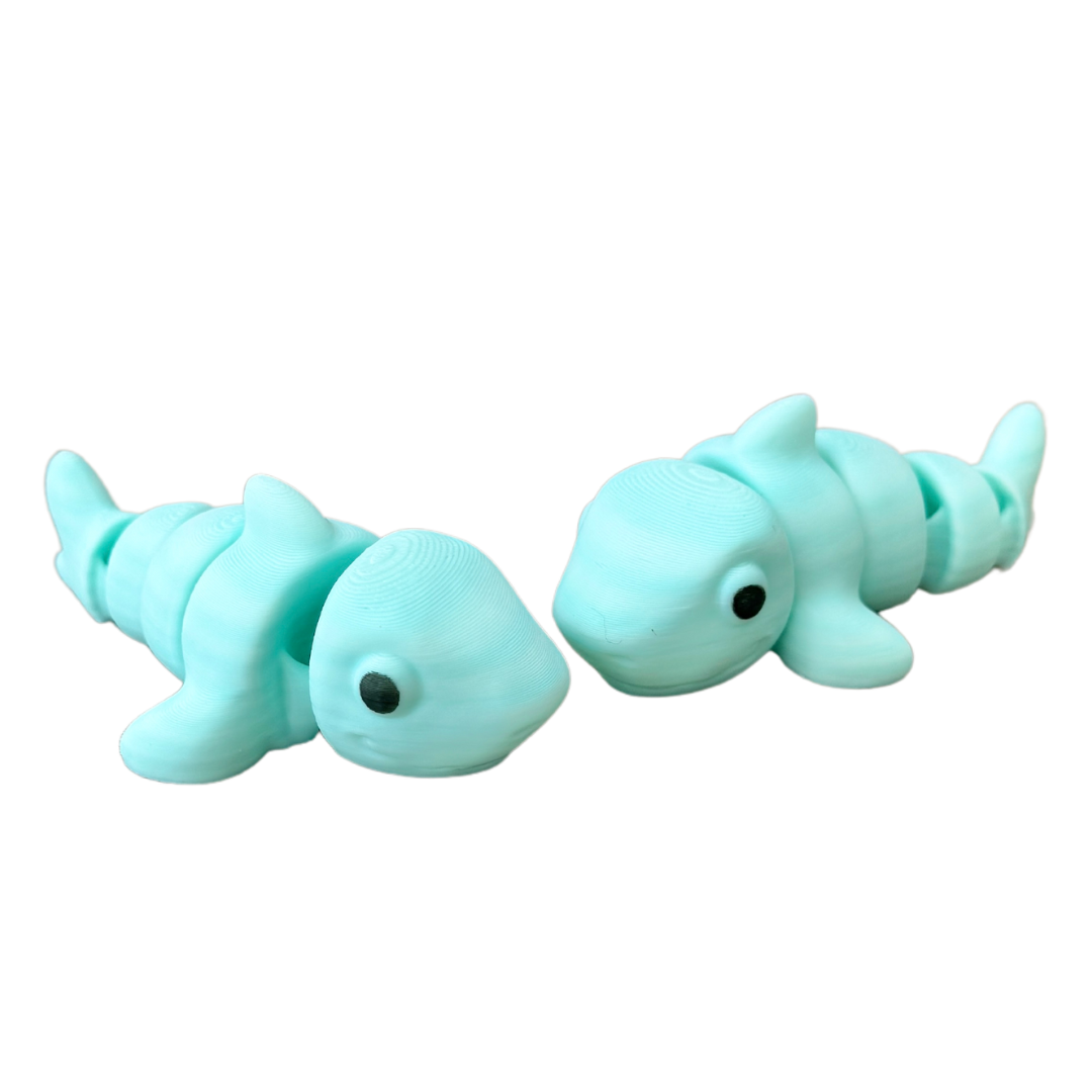 A small shark fidget toy with a blue-to-white gradient body, black eyes, and flexible articulation for sensory play