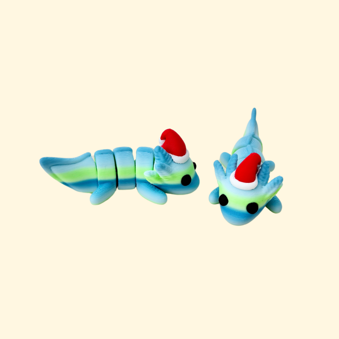 Axolotl fidget toy in gradient greens and blues with black eyes, wearing a red and white Christmas hat, 7cm in length.