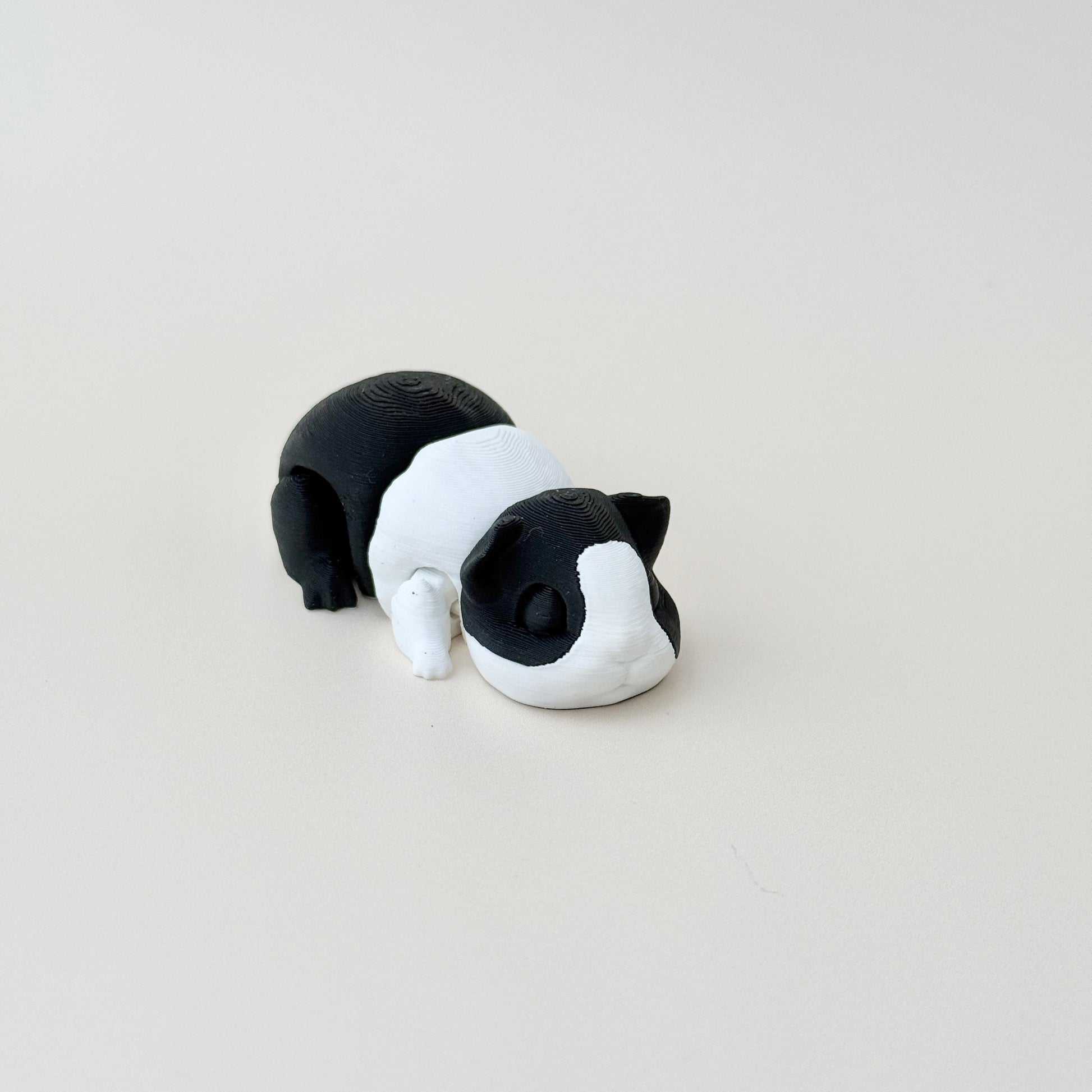 A cute guinea pig-inspired fidget toy in black and white with articulated features for sensory play.