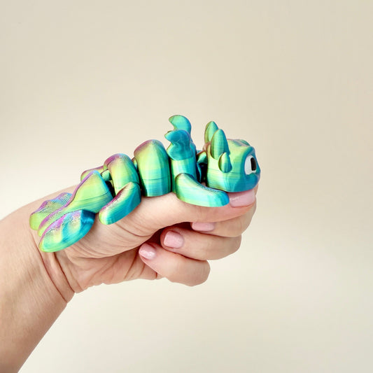 Colour-changing dragon fidget toy with shifting hues of gold, green, and purple, 12cm in length.