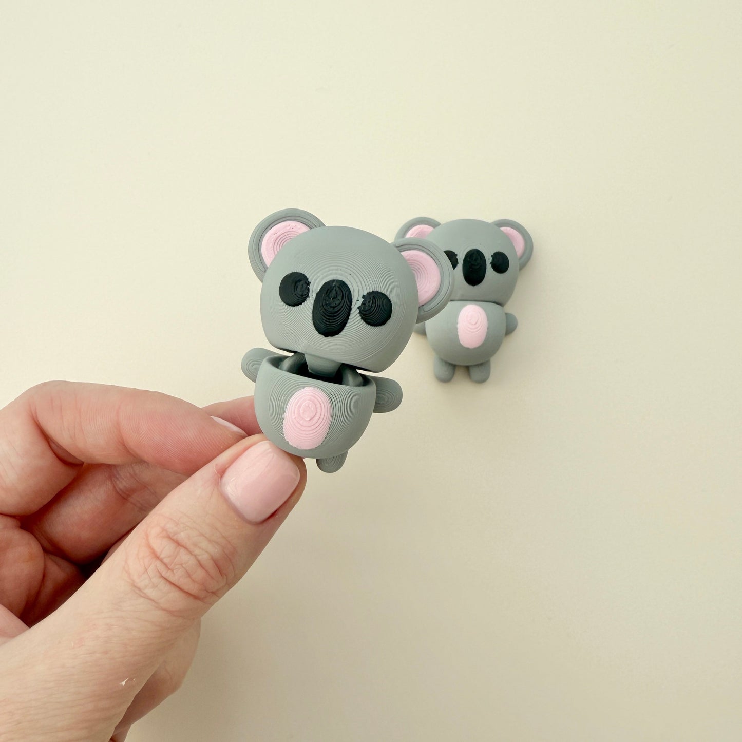 Compact koala fidget toy with grey body, pink tummy, and flexible design, ideal for fidgeting and stress relief