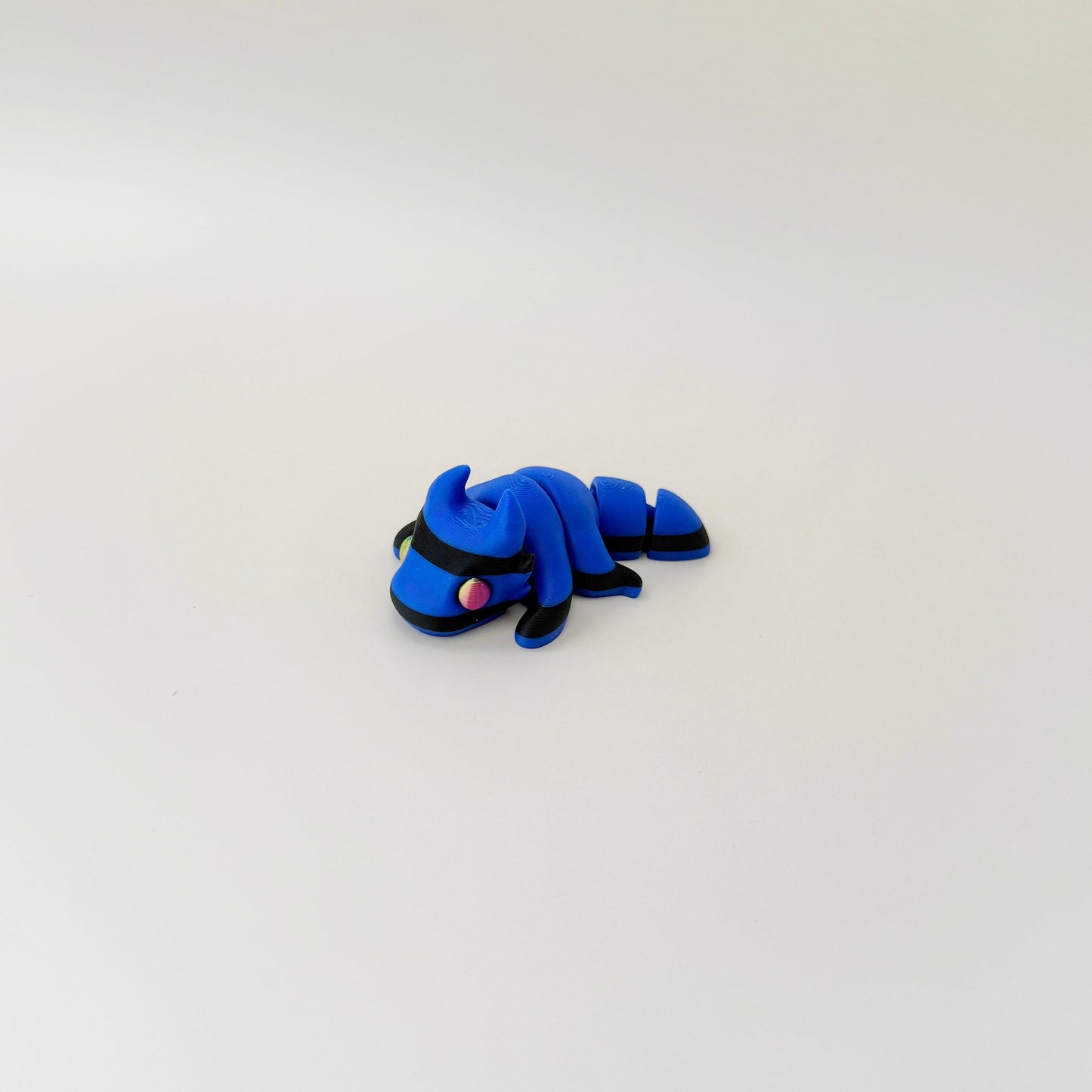 Fully articulated mini dragon fidget toy in dark blue with black stripes and colour-changing eyes.