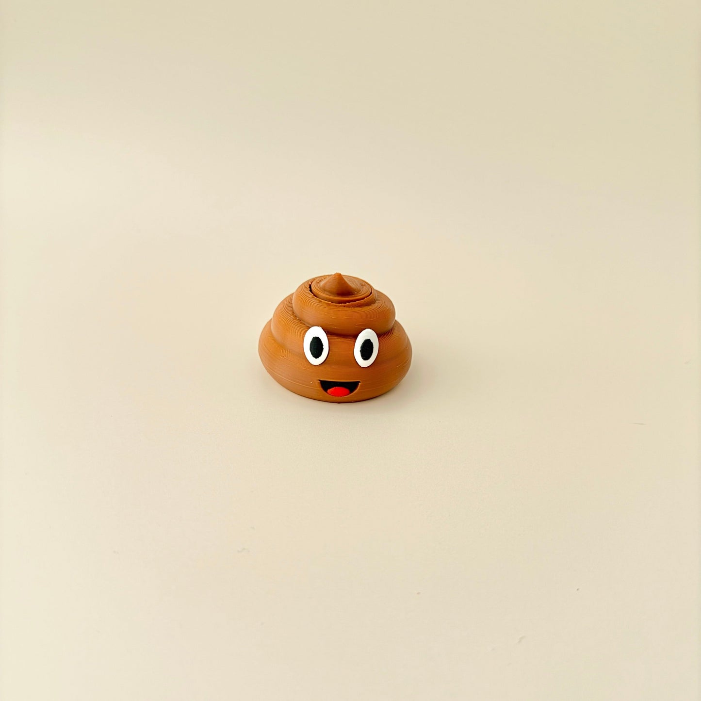 Brown poop-shaped fidget spinner with a playful design, including eyes and a cheeky smiley face.