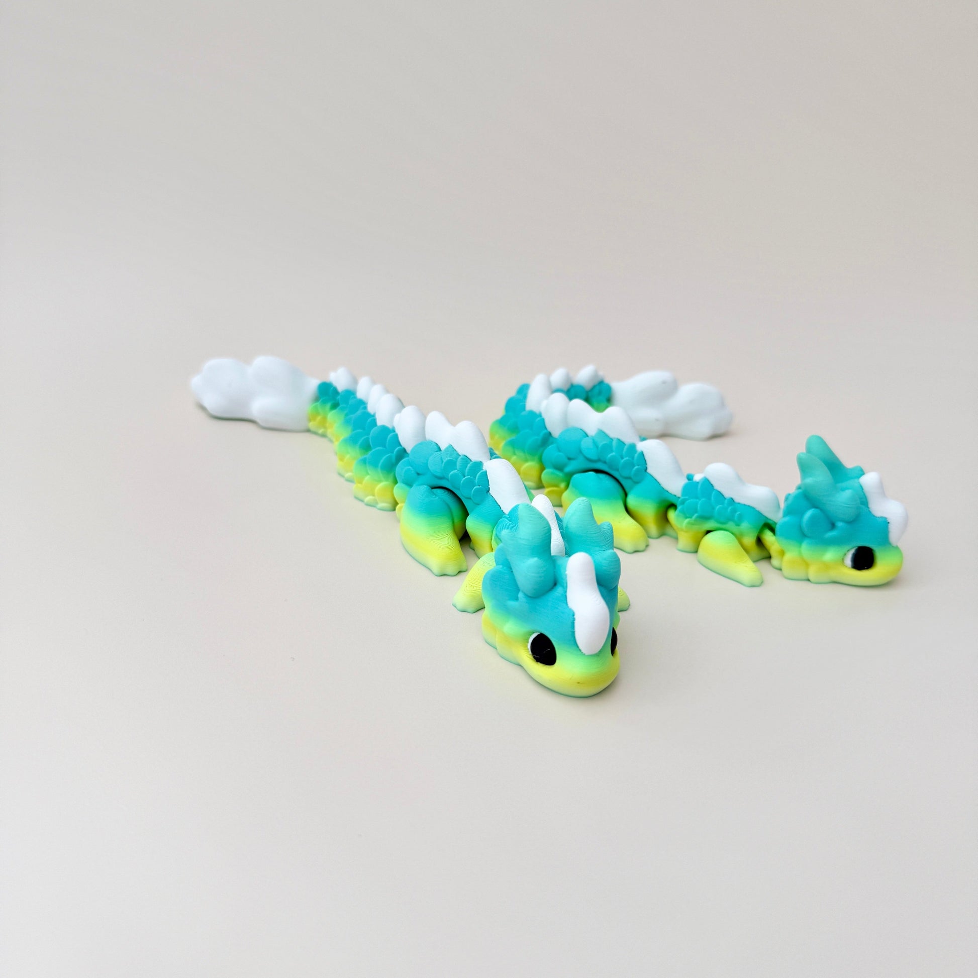 Kaida dragon fidget toy in yellow, blue, and green gradient with white spikes, designed for tactile engagement.