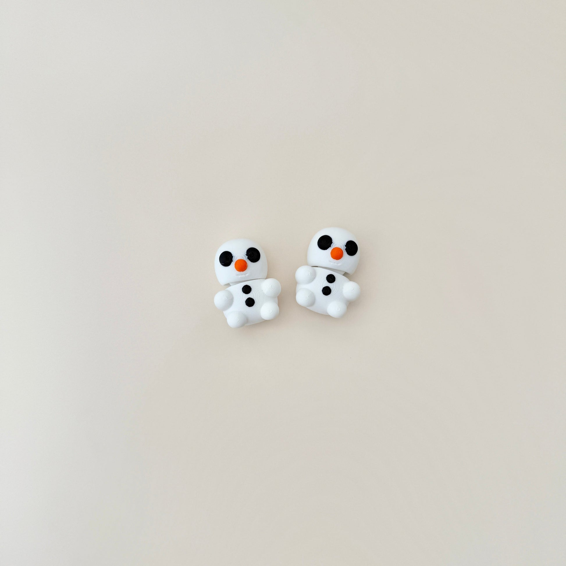 Small snowman fidget toy featuring black buttons, black eyes, an orange nose, and a cheerful smile.