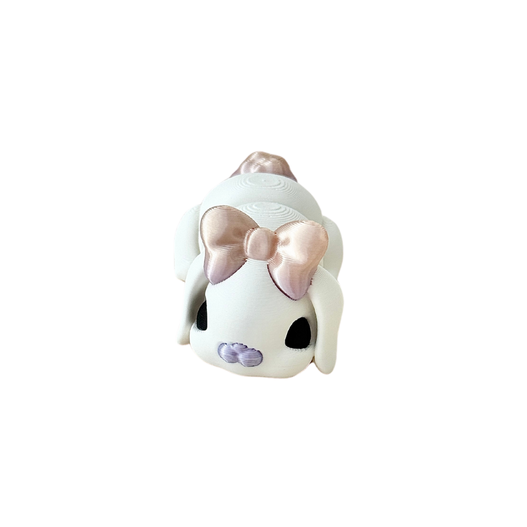 White bunny fidget toy with black eyes, featuring an iridescent nose, tail, and a bow on its head, 6cm in size.

