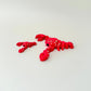 Red lobster fidget toy with white dots and a black eye, fully articulated for sensory play.