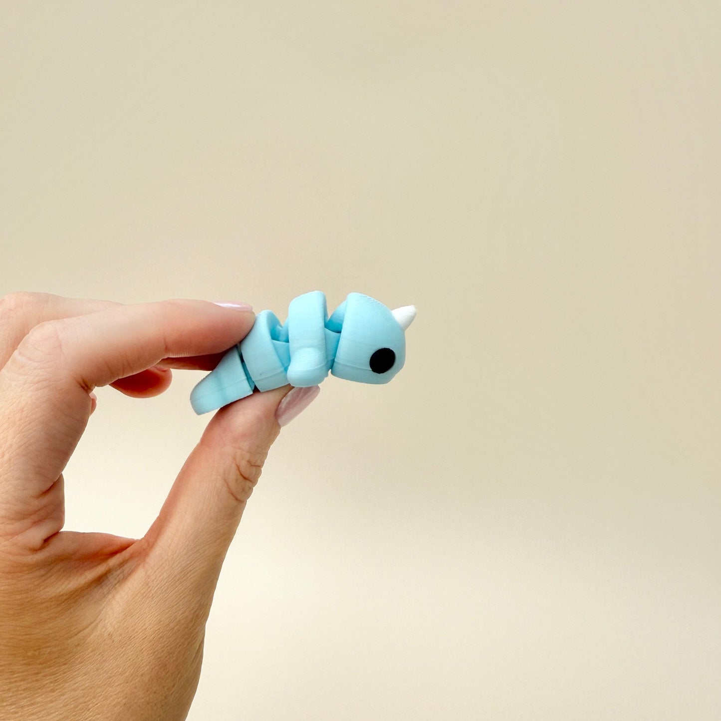 Compact narwhal fidget toy featuring a light blue body and a magical white horn.