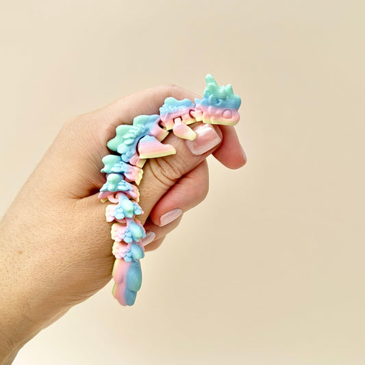 Mini Rainbow Dragon fidget toy with vibrant gradient colours and articulated body for sensory play.