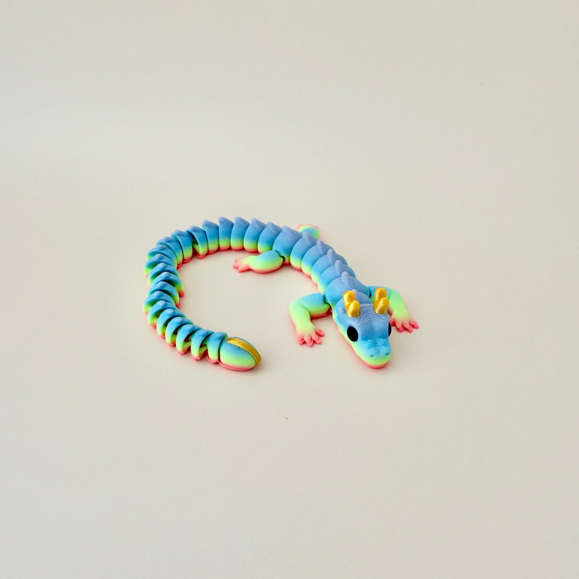 Mystic Dragon fidget toy in rainbow colours with gold horns and smooth, flexible movement.