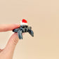 Luxury filament spider fidget toy with a festive red and white hat, glittery black and green accents.