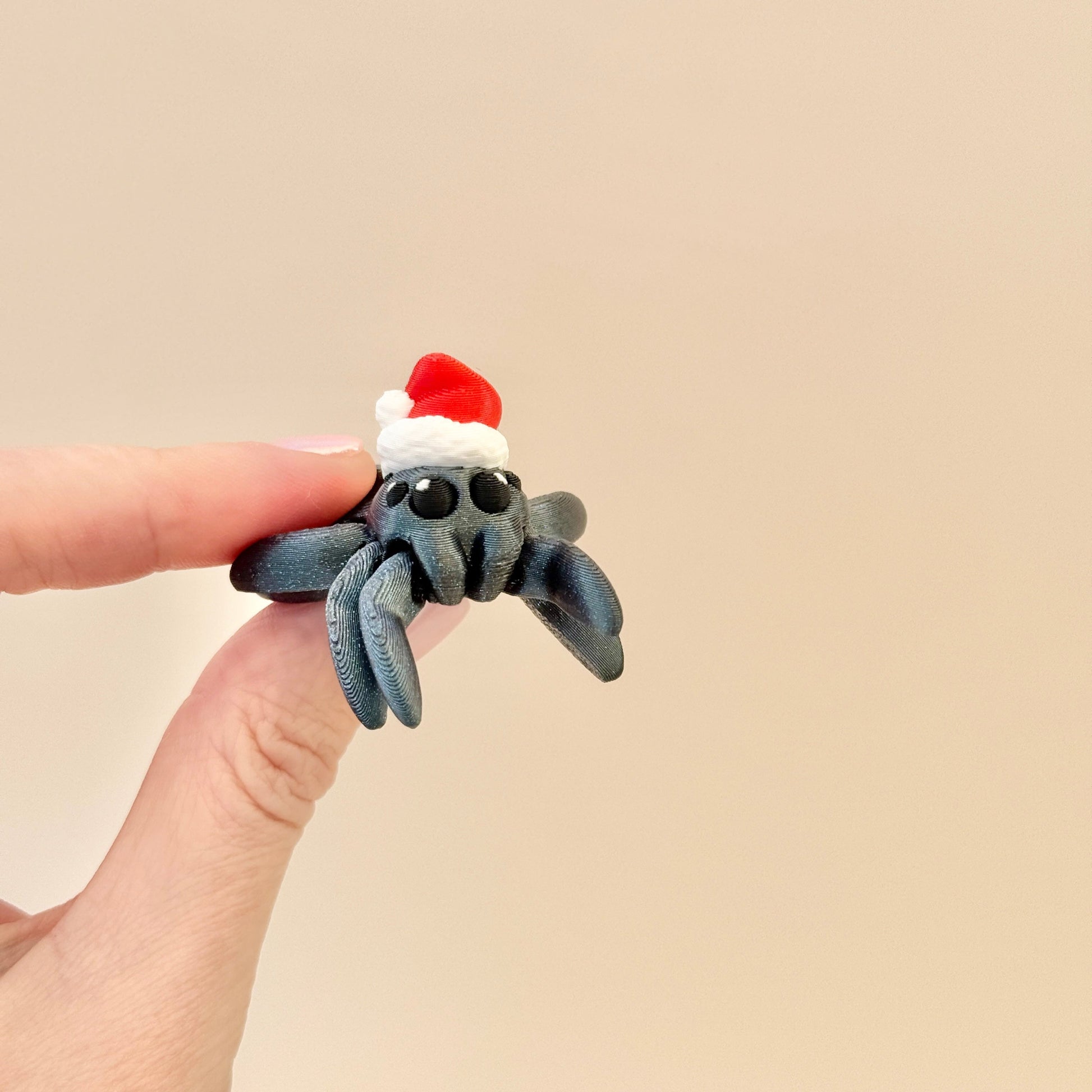 Luxury filament spider fidget toy with a festive red and white hat, glittery black and green accents.