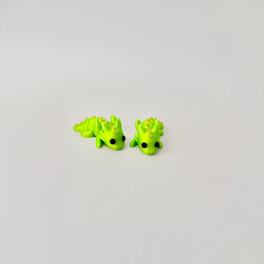 Luminous lime green baby dragon fidget toy, featuring black eyes and gold detailing, fully articulated.