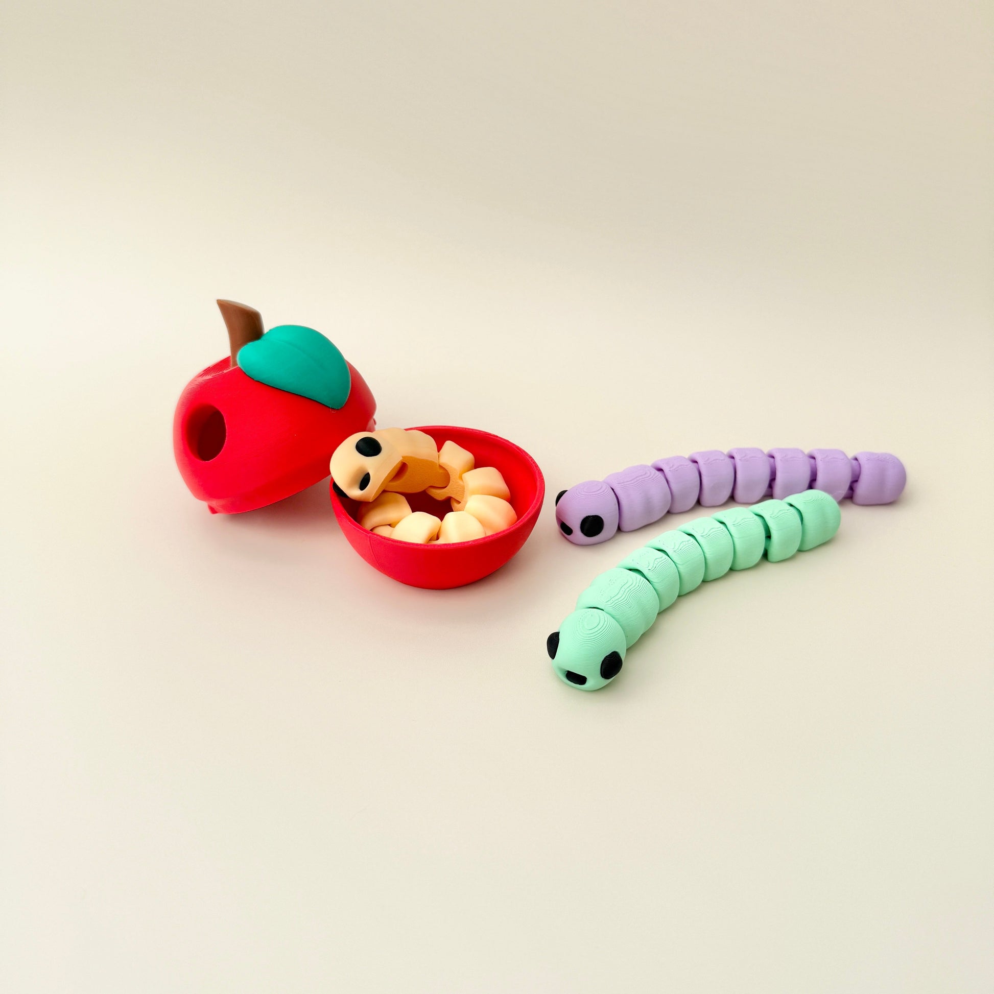 Articulated worm fidget toy placed inside a small apple container, perfect for carrying and play.