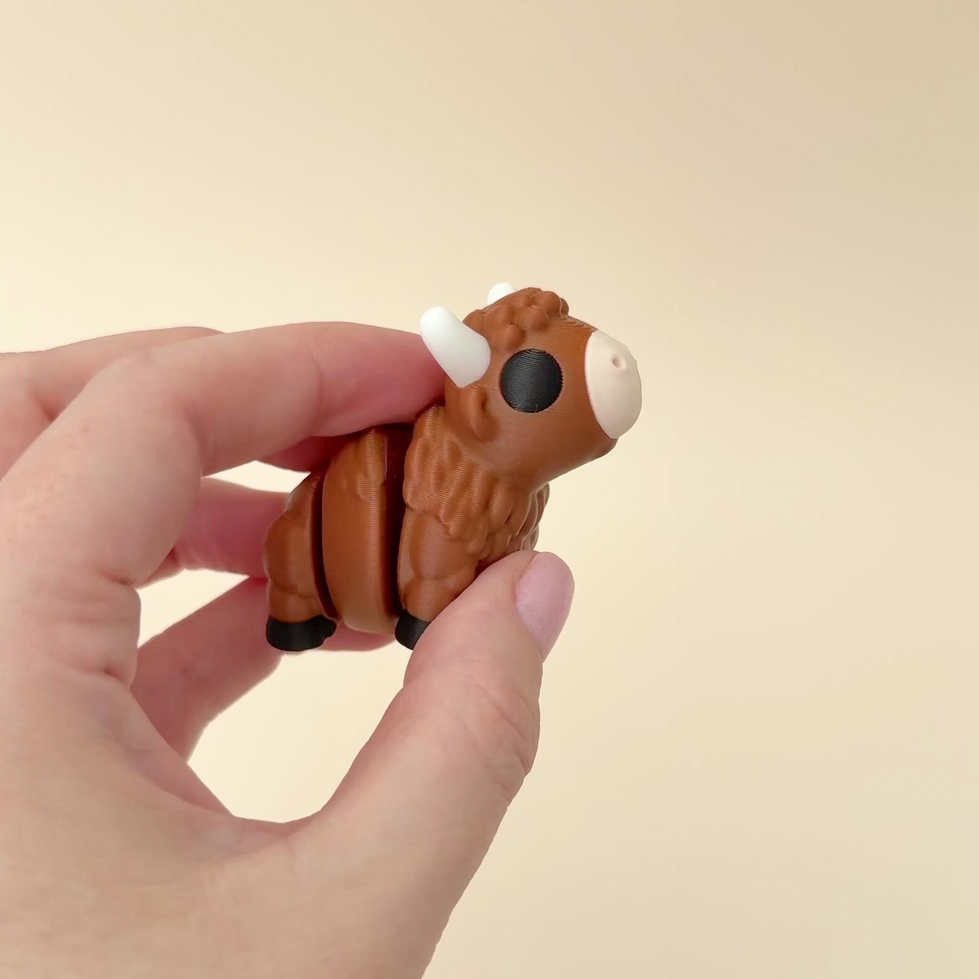 Small bison fidget toy featuring a realistic design with brown fur, white horns, and black details.