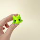 Green and gold baby dragon fidget toy with flexible body, black eyes, and detailed gold dots.